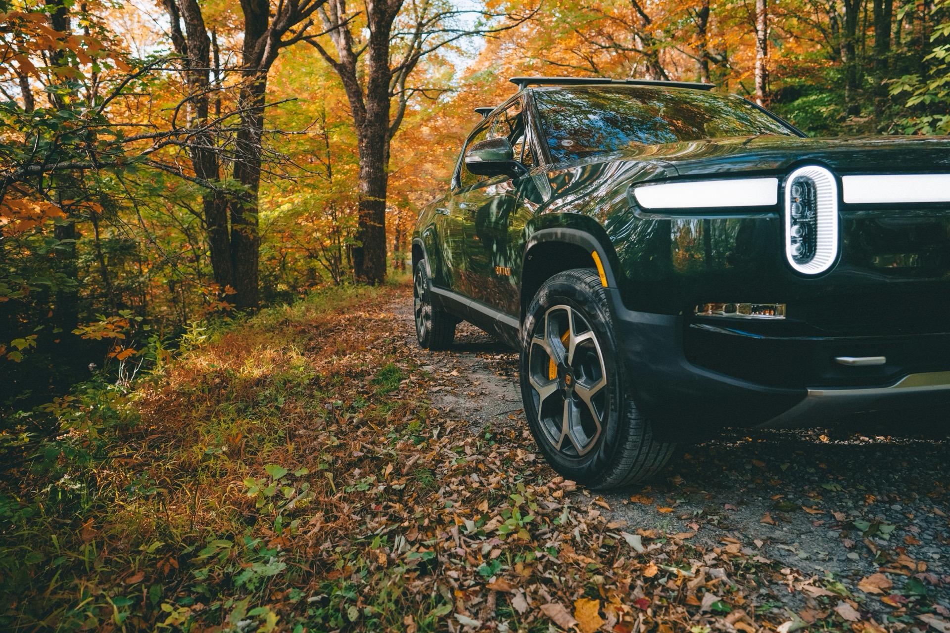 Dark green Rivian R1T on an autumn forest trail