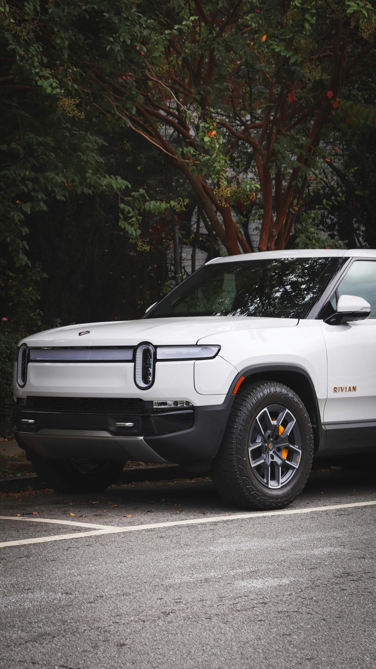 White Rivian R1T parked under trees